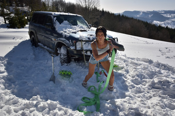 young athletic woman pulling car in winter