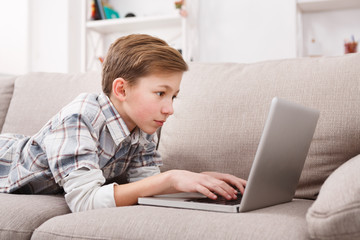 Teenage boy using laptop on couch at home