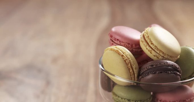 mixed macarons in glass bowl back slide reveal on table, 4k prores footage