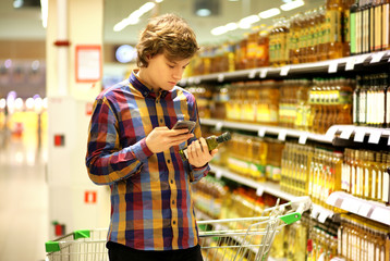 Man shopping in supermarket reading product information. Checking list.