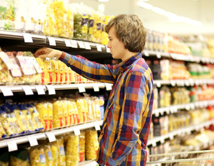 Man shopping in supermarket reading product information. Checking list.