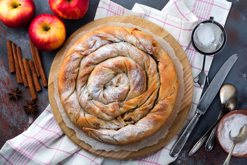 Round burek pie with an apple on a dark background. Traditional Serbian cuisine. Selective focus. Top view.