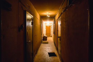Fototapeta na wymiar Dirty empty dark corridor in apartment building, doors, lighting lamps