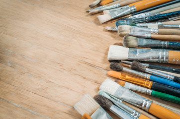 Fototapeta premium Bunch of old artist paintbrushes on wooden rustic table with space for text