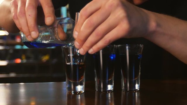 bartender preparing and lining shot glasses for alcoholic drinks on bar