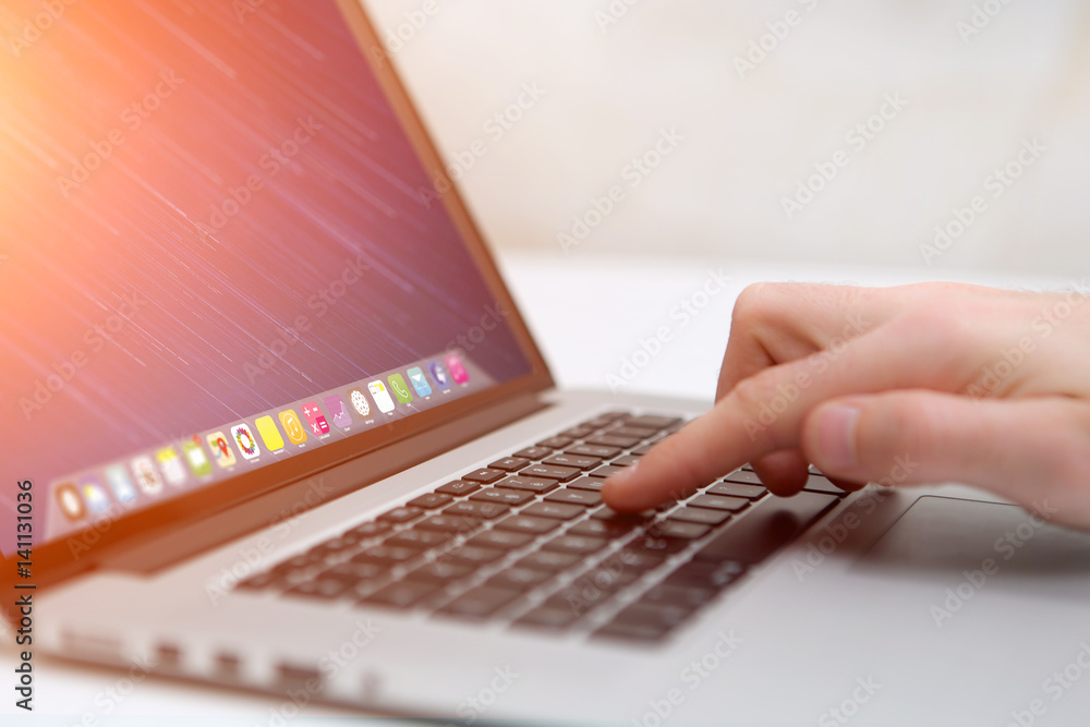 Wall mural hand typing on a keyboard of laptop with operating system screen on background