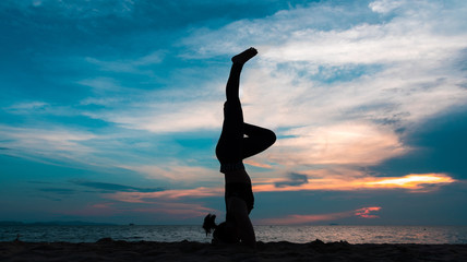 Silhouette of a woman playing yoga on twilight. Sunset sky background