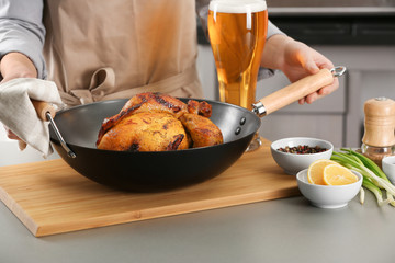 Woman with grilled beer can chicken in pan on table