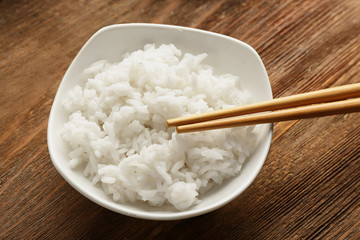 Bowl of rice and chopsticks on wooden table