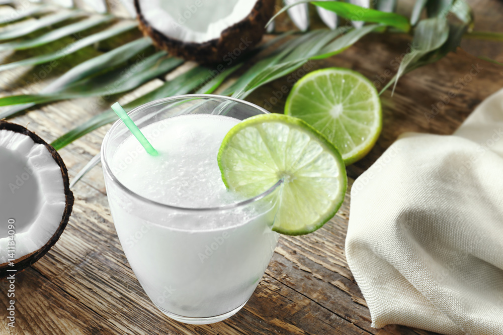 Wall mural Glass of fresh coconut milk with lime on wooden table