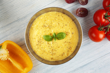Bowl with tasty cheese sauce and different products on wooden background