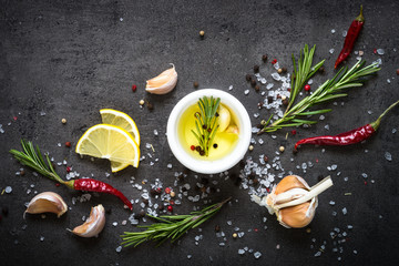 Selection of spices herbs and greens. Rosemary basil lemon olive oil pepper top view black background.