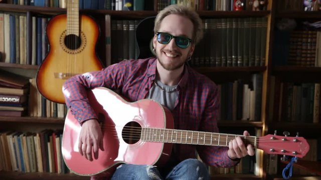 Man Playing small Acoustic Guitar in sun glass. Playing on acoustic pink guitar.