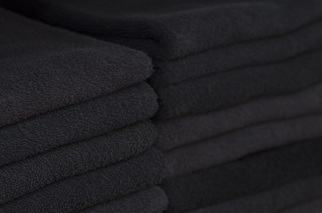 Two piles of black towels laying in the closet