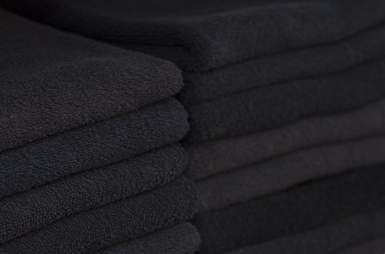 Two piles of black towels laying in the closet