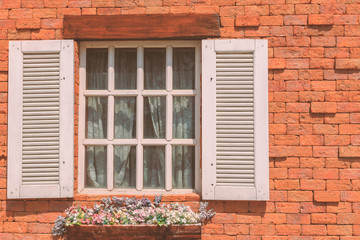 White window with flower pot on brick wall