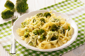 Vegetarian food - pasta with broccoli and cheese on wooden background.