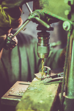 Worker drilling holes in a steel part. Small metal manufacture of   steel accessories.