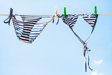 Striped female swim suit is dried on clothesline