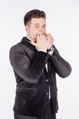 business man biting his nails fingers freaking out. human emotion expression and lifestyle concept. image on a white studio background..