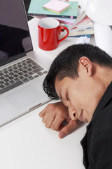 Businessman stressed and fall asleep on the tableat work on white background