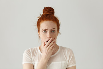 Portrait of surprised amazed attractive young redhead female wearing white top having astonished...