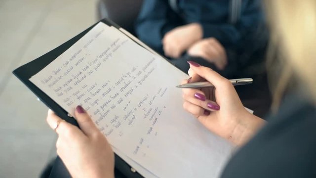Woman psychologist making notes during therapy session with boy