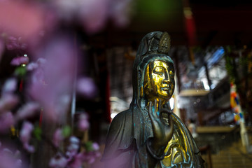 Golden Buddha statue with purple flowers in a temple in Colombo, Sri Lanka