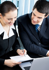 Two businesspeople signing document at office