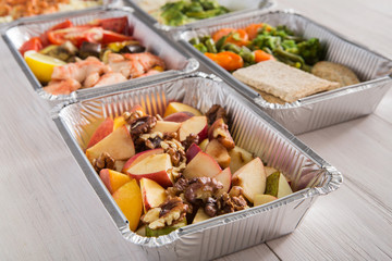 Healthy food take away in foil boxes on wood background