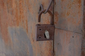 Hack padlock on the rusty iron door in a brick house