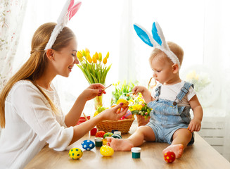 Happy easter! family mother and baby son paint eggs for holiday Easter