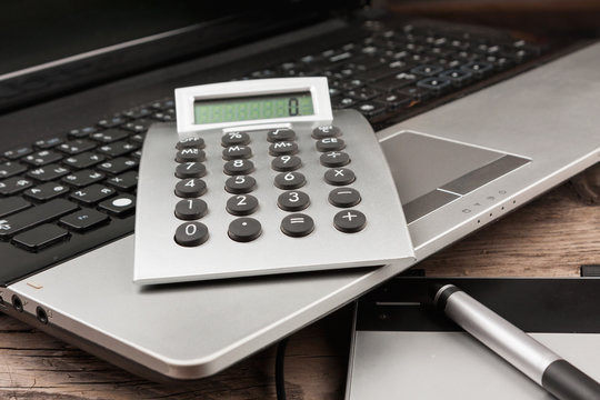 Laptop with a calculator and a graphic tablet on a wooden table.