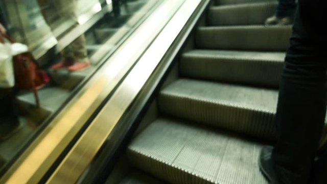 Defocussed unrecognizable people rush on escalator in underground train station
