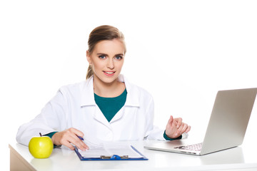 Young female student doctor sitting with a laptop on a white background