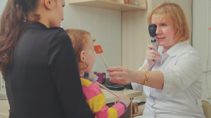 Optometrist checks child's eyesight - mother and child in ophthalmologist room