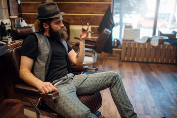 Brutal bearded barber with straight razor in hand
