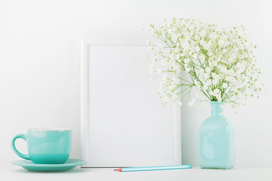 Mockup of picture frame decorated flowers in vase and coffee cup on white table with clean space for text and design your blogging.