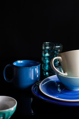 Set of dishes. blue cups, glass and plates on the dark background