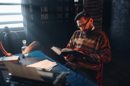 Bearded author in glasses reading a book