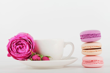 Fototapeta na wymiar Mockup of coffee cup with rose flower and stack of macaroon on white table with empty space for text and design your blogging.