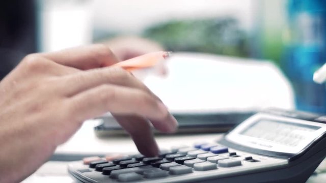 Men's hands typing on calculator