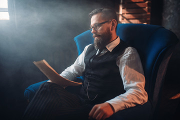 Bearded writer in glasses reads handwritten text