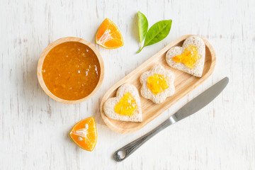 Orange jam with bread set on white rustic wooden table background