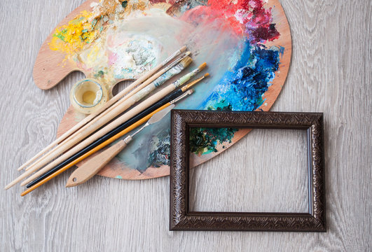 Materials for creativity, palette and brush for painting on a wooden background. The concept of fine art.