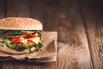 Delicious fresh homemade burger with chicken nuggets and avocado on a wooden table