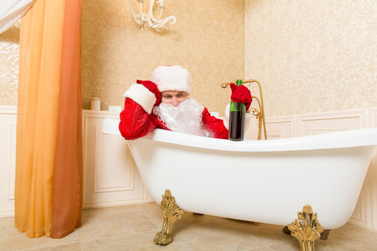 Drunk Santa Claus with bottle sleeping in a bath