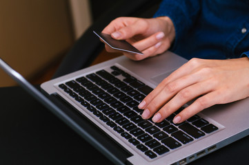 Woman's hands holding a credit card and using laptop for online shopping