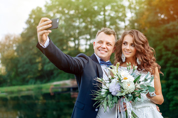 Beautiful happy husband and wife do selfie on wedding day