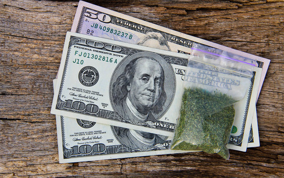 Dollars and marijuana in packet on wooden background
